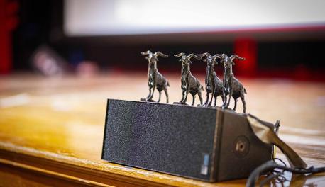 A series of small goat figurines sit on a speaker.