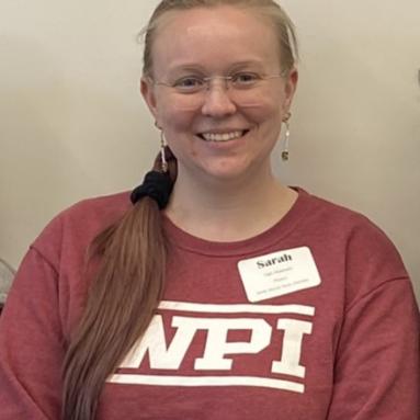 A picture of Sarah. She has her hair in a ponytail pulled to her right shoulder. She is wearing glasses and a WPI shirt. 