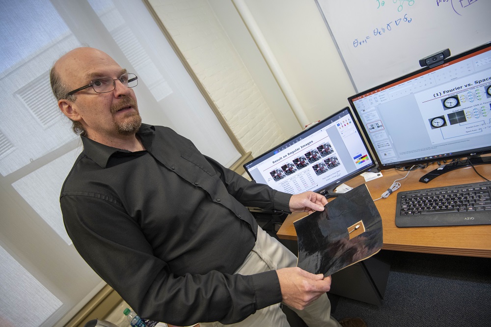 Randy Paffenroth, associate professor of mathematical sciences at WPI, holds a carbon-based sheet known as Miralon®, which is used in a variety of spacecraft applications.