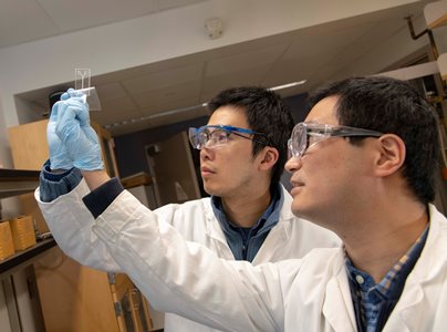 PhD candidate  Yundong Ren, right, and mechanical engineering professor Shawn Liu examine a microfluidic device designed to direct samples to the biosensor.