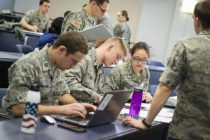 WPI Air Force ROTC cadets Miles Schuler, Brian Gasco and Brittany Kyer plan a solution to a hypothetical cyber threat during the exercise, while U.S. Army Maj. Francisco Escobar, assistant professor of military science, reviews a data folder related to the lab.