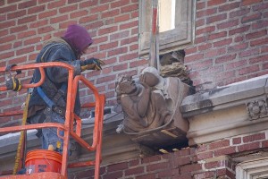 With the mortar removed from around the 500-pound grotesque, a worker readies it for lowering by crane.