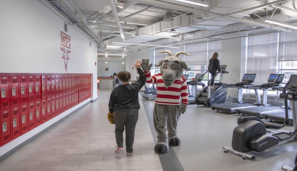Gompei the goat mascot high fiving a woman in the rec center.