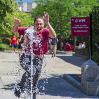 WPI student jumping through fountain and laughing