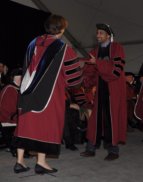 President Laurie Leshin handing diploma to student.