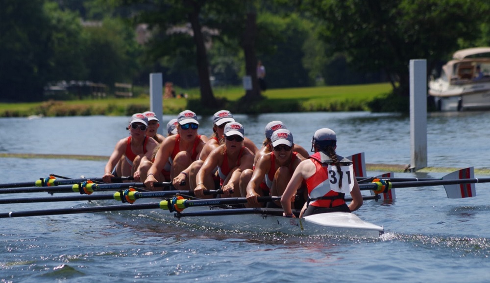 Eight women rowers are directed by a coxswain on the water.