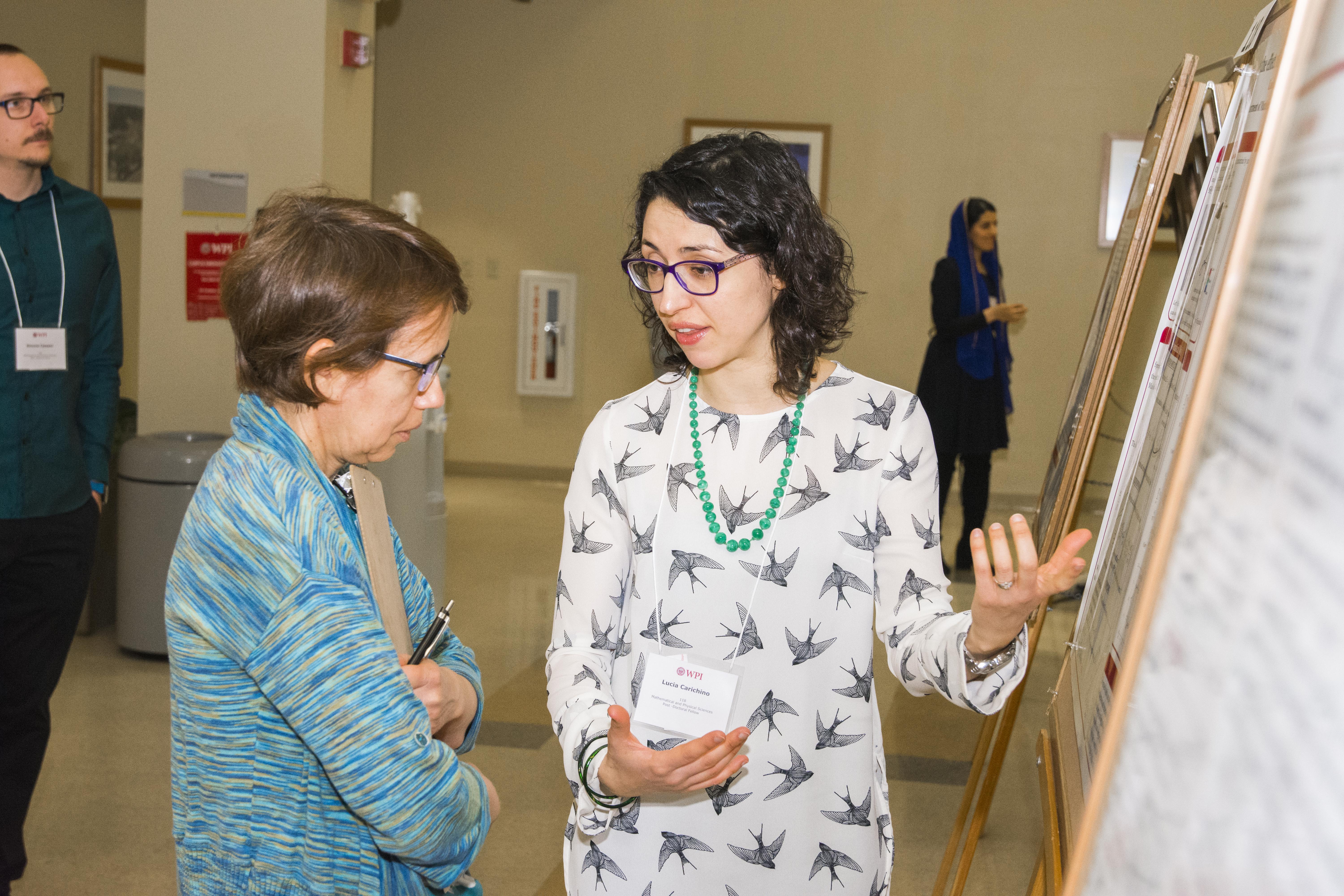 A student describes her work to a judge while gesturing toward her poster board.