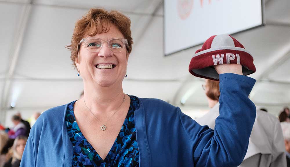 A proud mother stands underneath the Commencement tent and holds up her son's beanie from his first year at WPI.