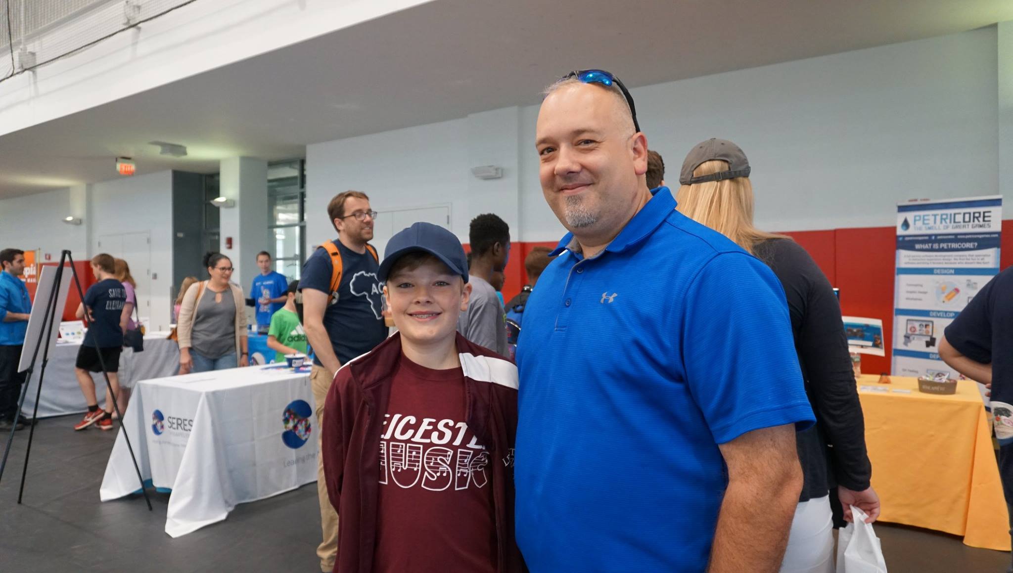 A father (right) and son smile together in the Sports & Rec Center while taking a break from some of the TouchTomorrow activities.