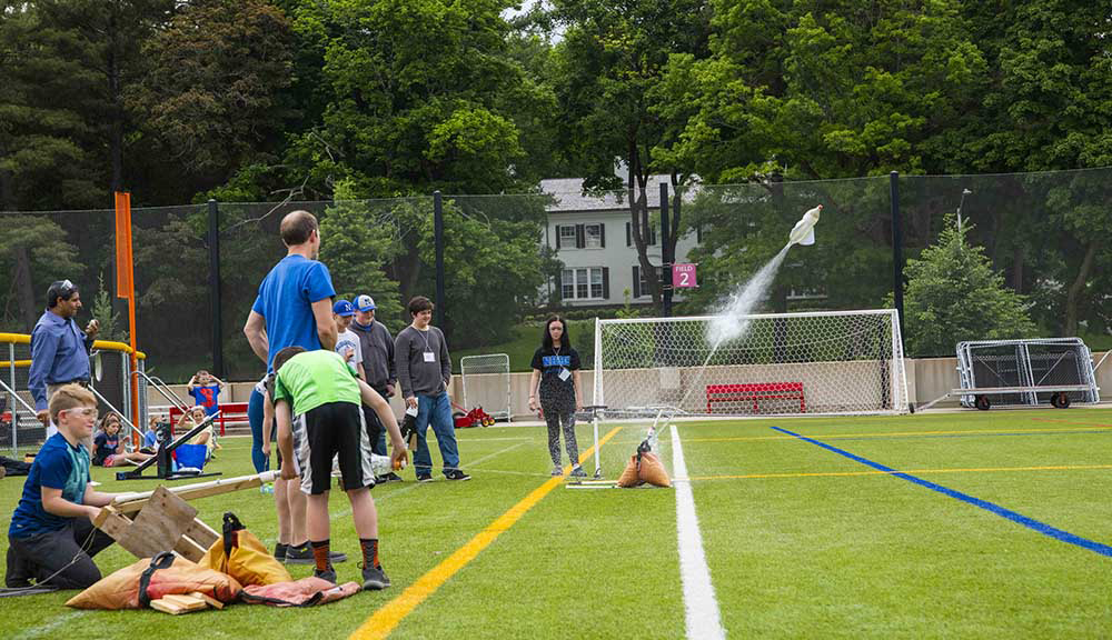 Student participants in the Goddard Cup gather on the rooftop field and watch as a rocket is launched into the air using non-combustible water.