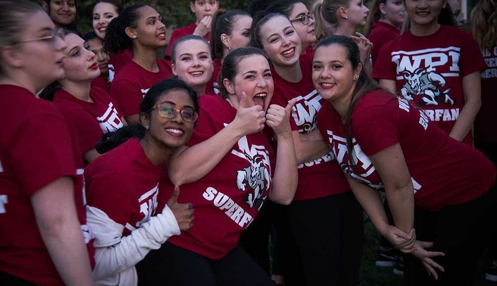 A group of students wearing WPI Superfan shirts gathers for a photo, laughing and smiling, during Homecoming 2018.
