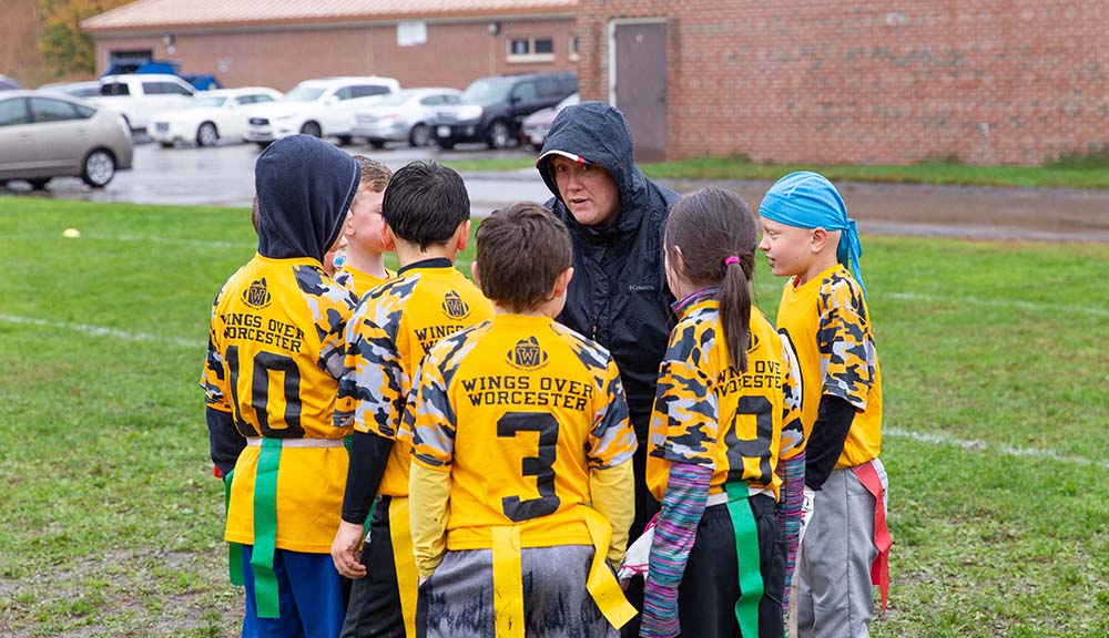 Susan Roberts huddles up with members of the flag football team she coaches.
