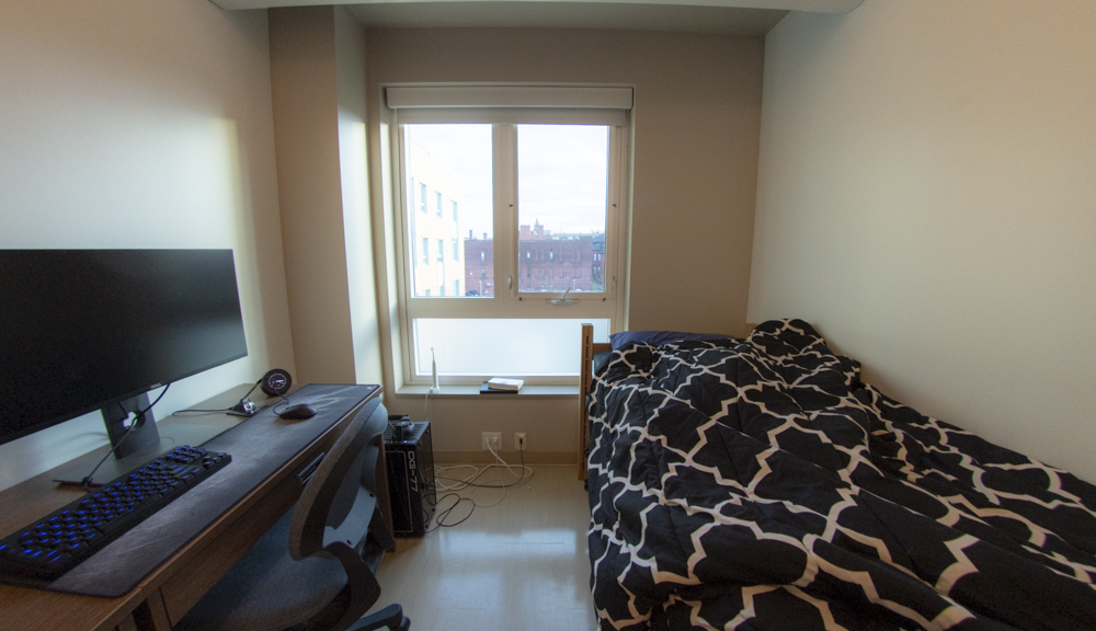 Central view of room with bed, window, and desk.