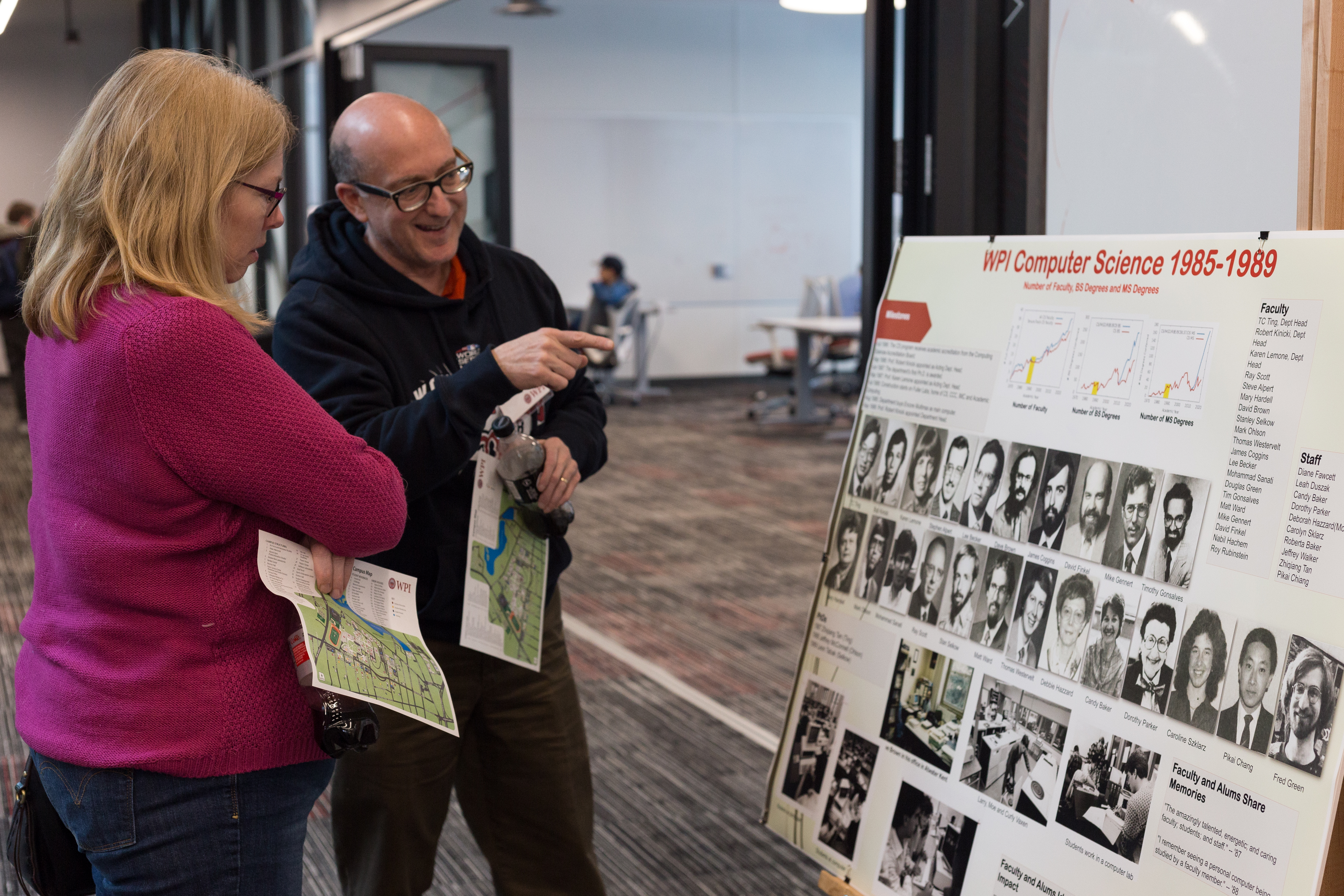 Two attendees study a poster on display in the Foisie Innovation Studio.