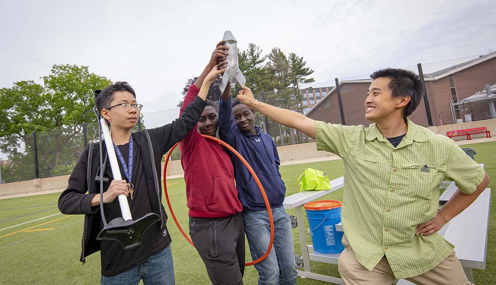 Participants in the Goddard Cup gather around their water rocket on the rooftop field.
