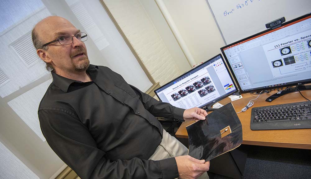 Randy Paffenroth shares some of his research with two computer screens behind him.