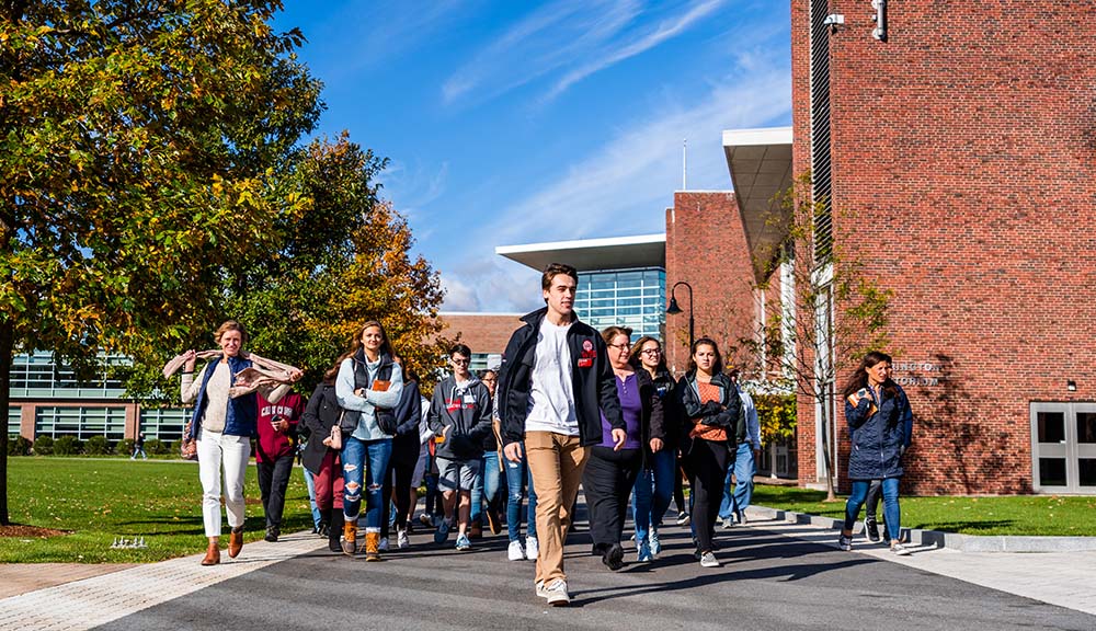 A current WPI student leads a group of prospective students and their families in front of Harrington Auditorium on a tour.