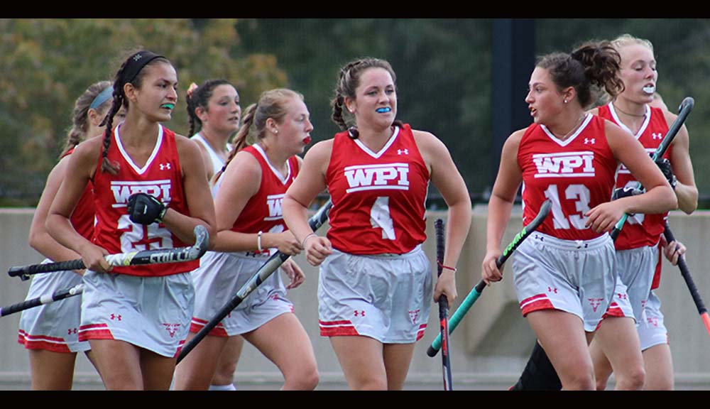 Members of the field hockey team run down the field during a game.