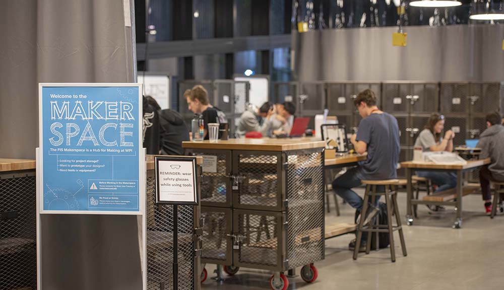 A photo of students working in the Makerspace, with a blue sign reading "Welcome to the Makerspace" in the left hand corner.