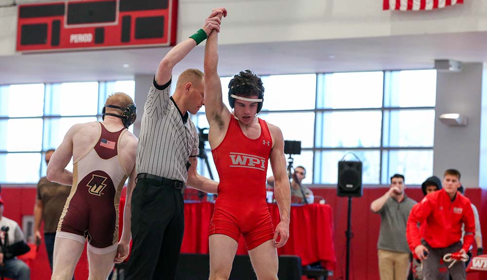 A referee holds up the hand of a victorious WPI wrestler.