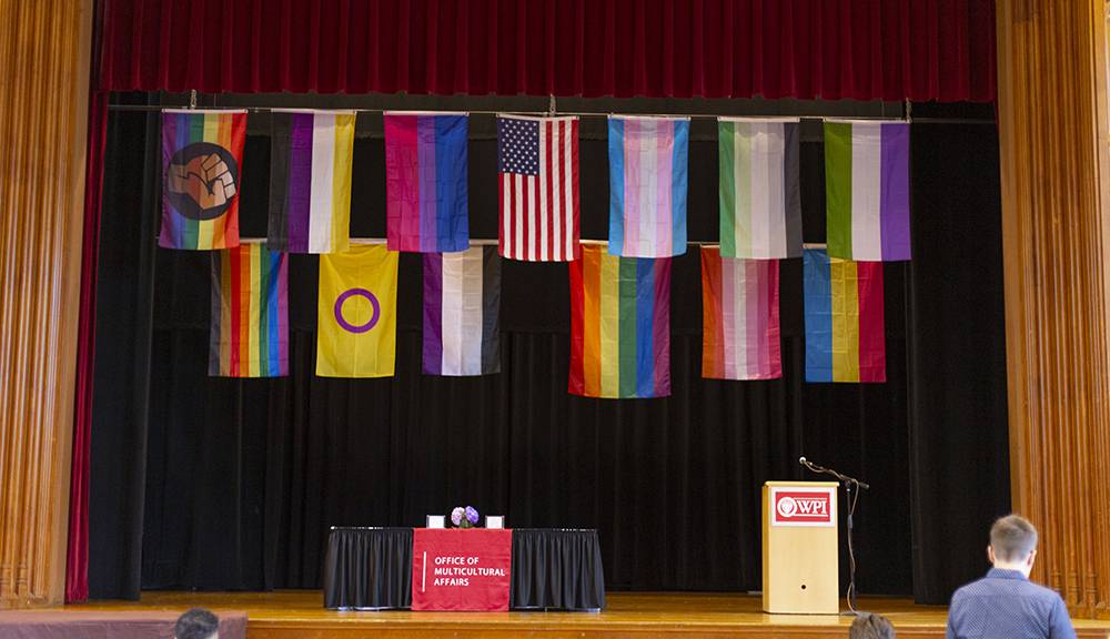 stage with an award table, podium, and flags for each sexual and gender identity hung above 