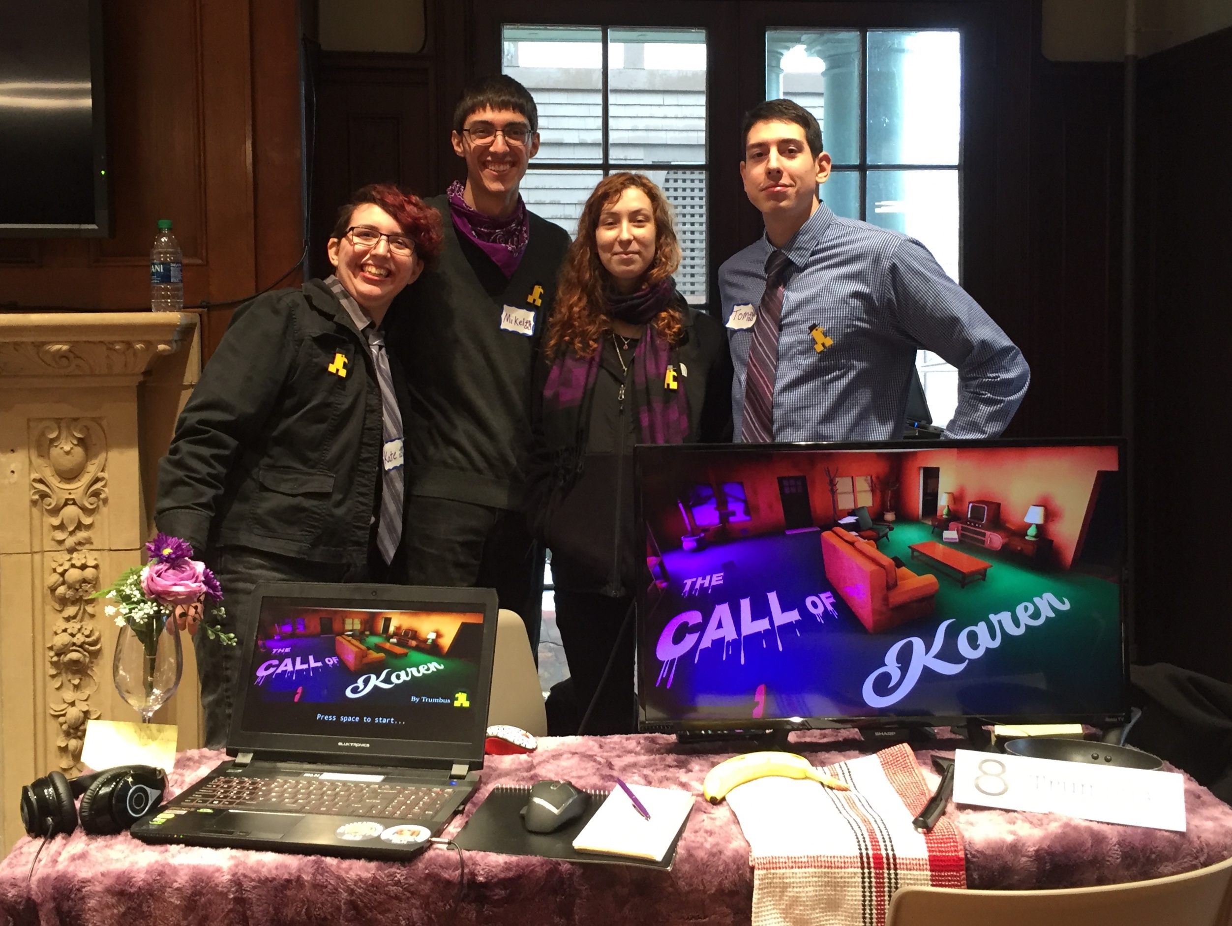 four students on MQP team standing near their product the Call of Karen in a booth