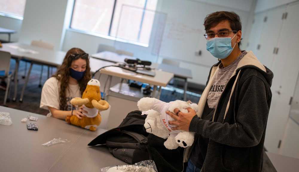 Two students build their own stuffed animal plushies at a special event.