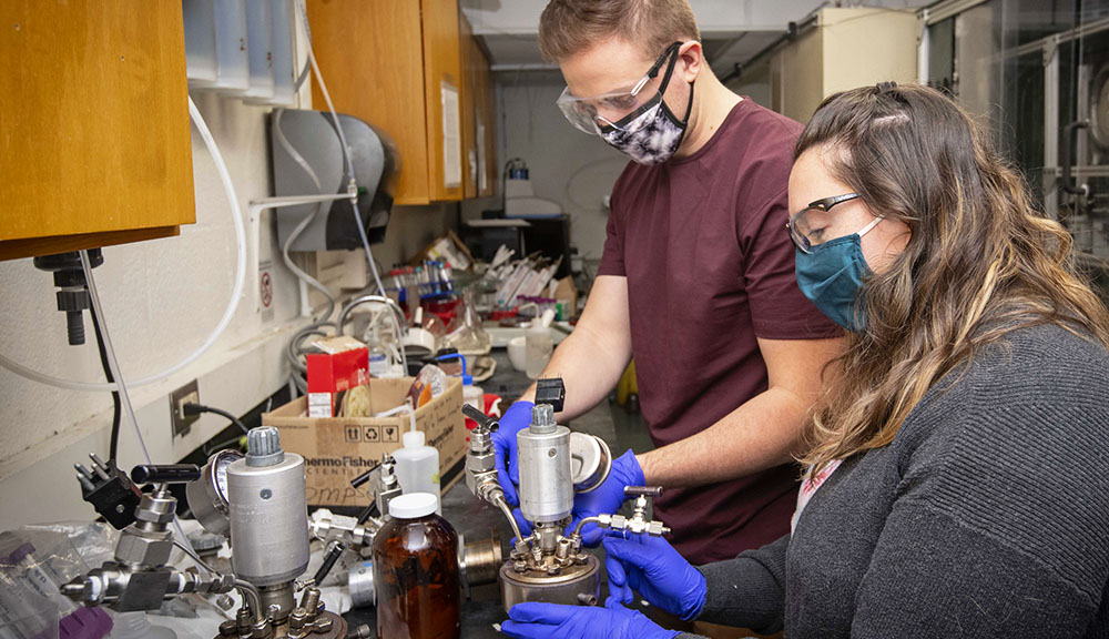 WPI PhD candidate Heather LeClerc (foreground) and WPI PhD student David Kenney work together to seal and prepare the reactor used to produce bio-oil from toxic sludge.