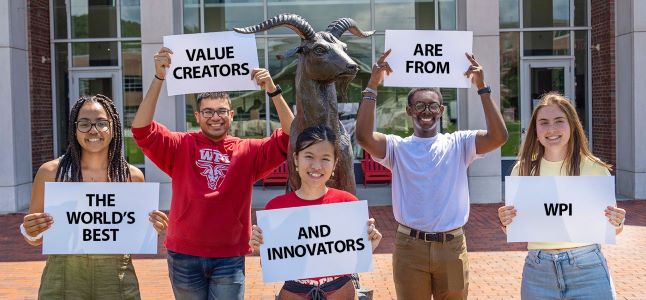 students holding signs that say The world's best value creators and innovators are from WPI