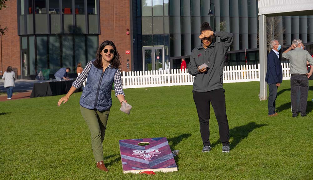Two WPI staff members play a game of corn hole on the Quad.