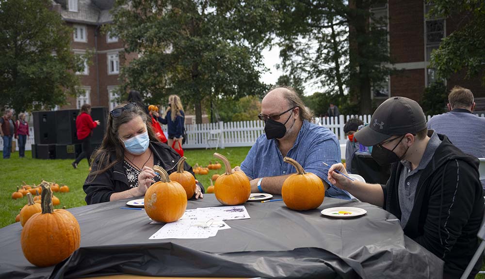 A family gathers to paint pumpkins on the Quad as part of Family Weekend.