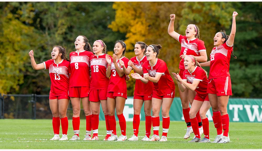 Members of the women's soccer team cheer during a game.