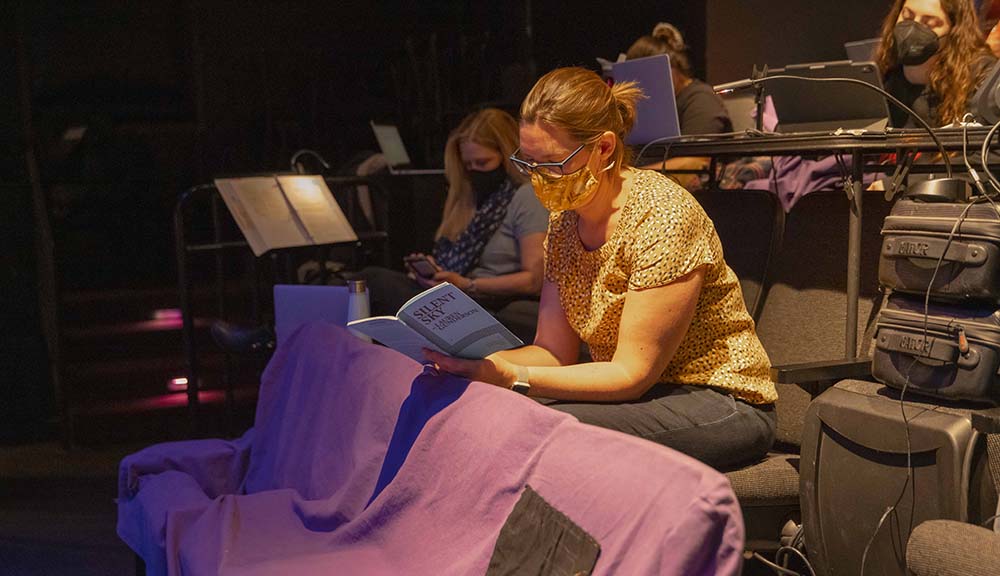 A student reviews the Silent Sky play booklet during a rehearsal.