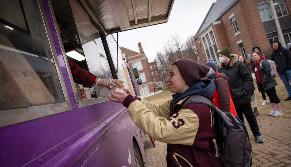A student picks up a meal from a food truck on campus.