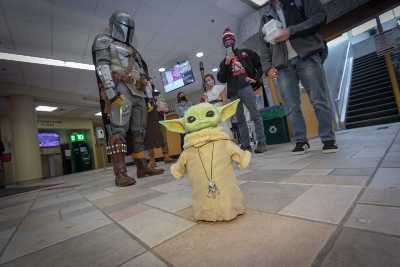 Students watch a baby Yoda in the campus center. alt