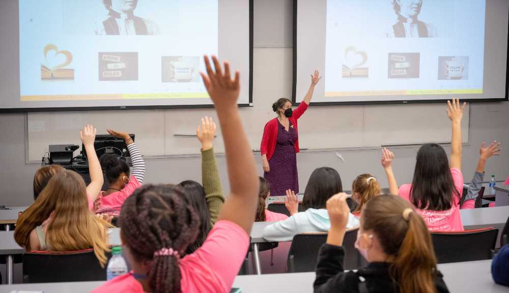 Young students raise their hands in a classroom during a K-12 event.