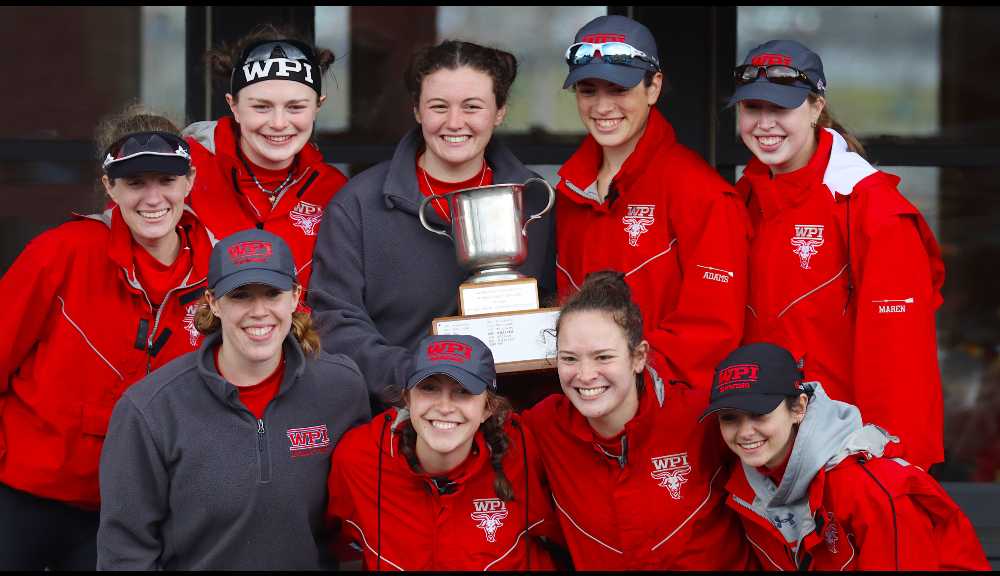 Members of the women's rowing team pose with a trophy.