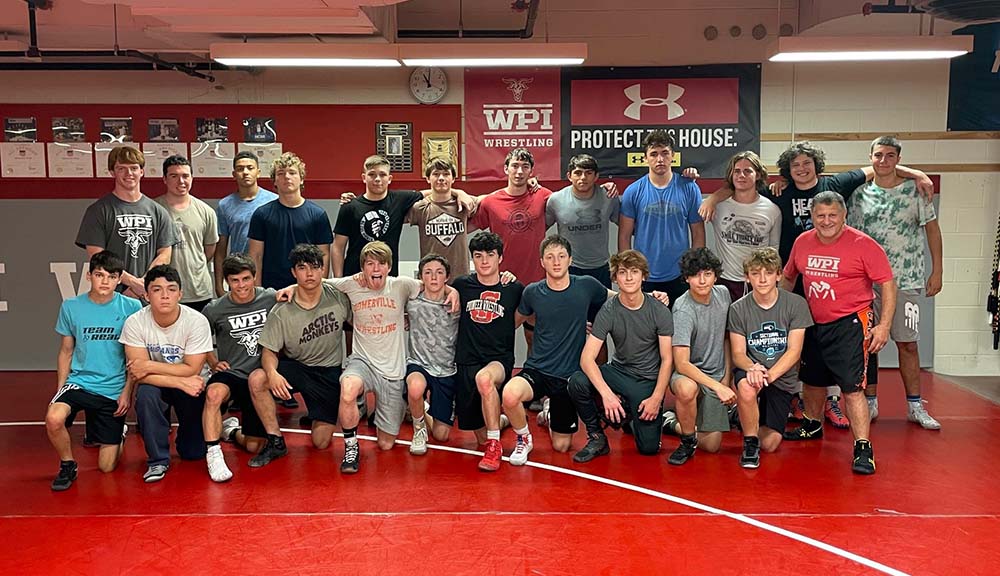 Participants at a wrestling camp gather for a group photo in the gym.