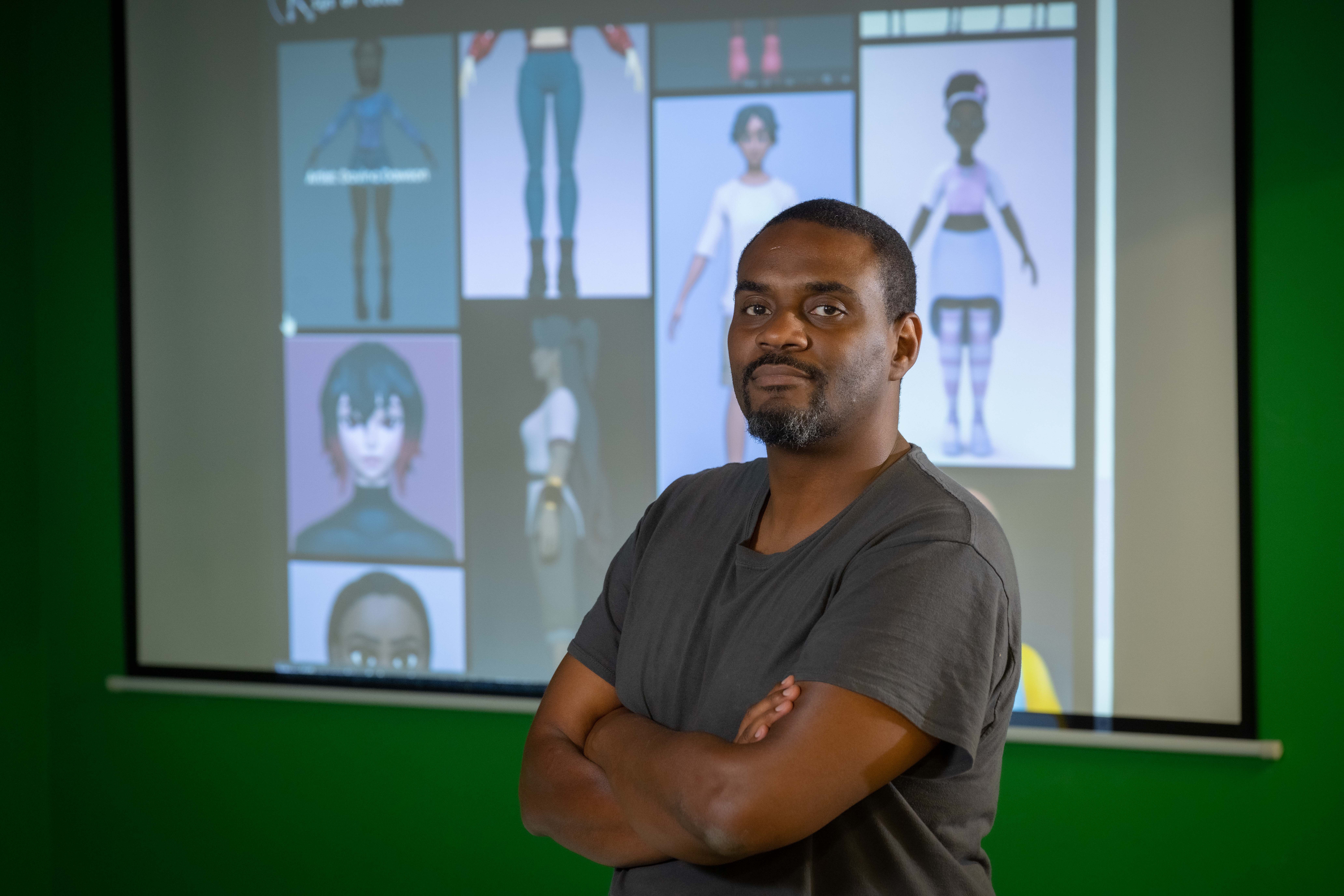 IMGD Associate Professor of Teaching Farley Chery stands in front of rigs of color images.