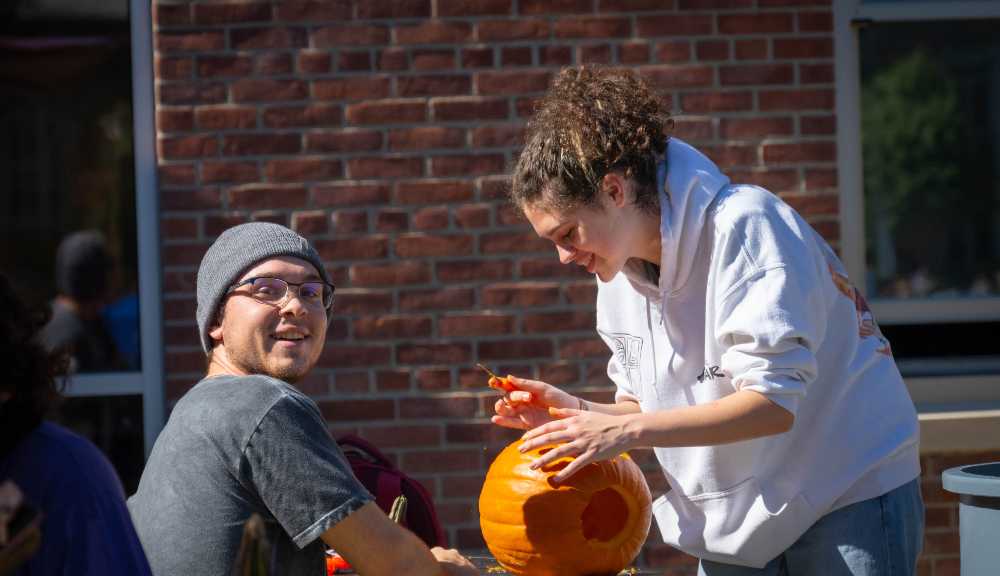 Students carve a pumpkin together during Fall Fest.