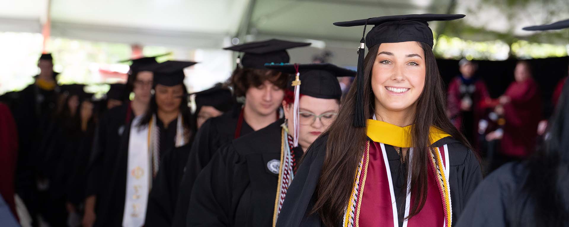 A graduate smiles in her regalia on Commencement day.