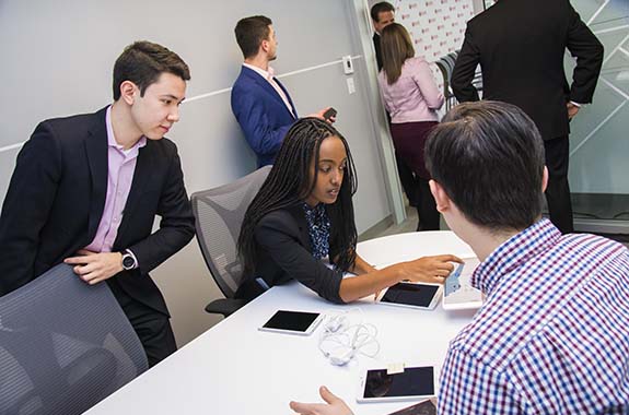 Students gather around a smart device in a meeting space at WPI.