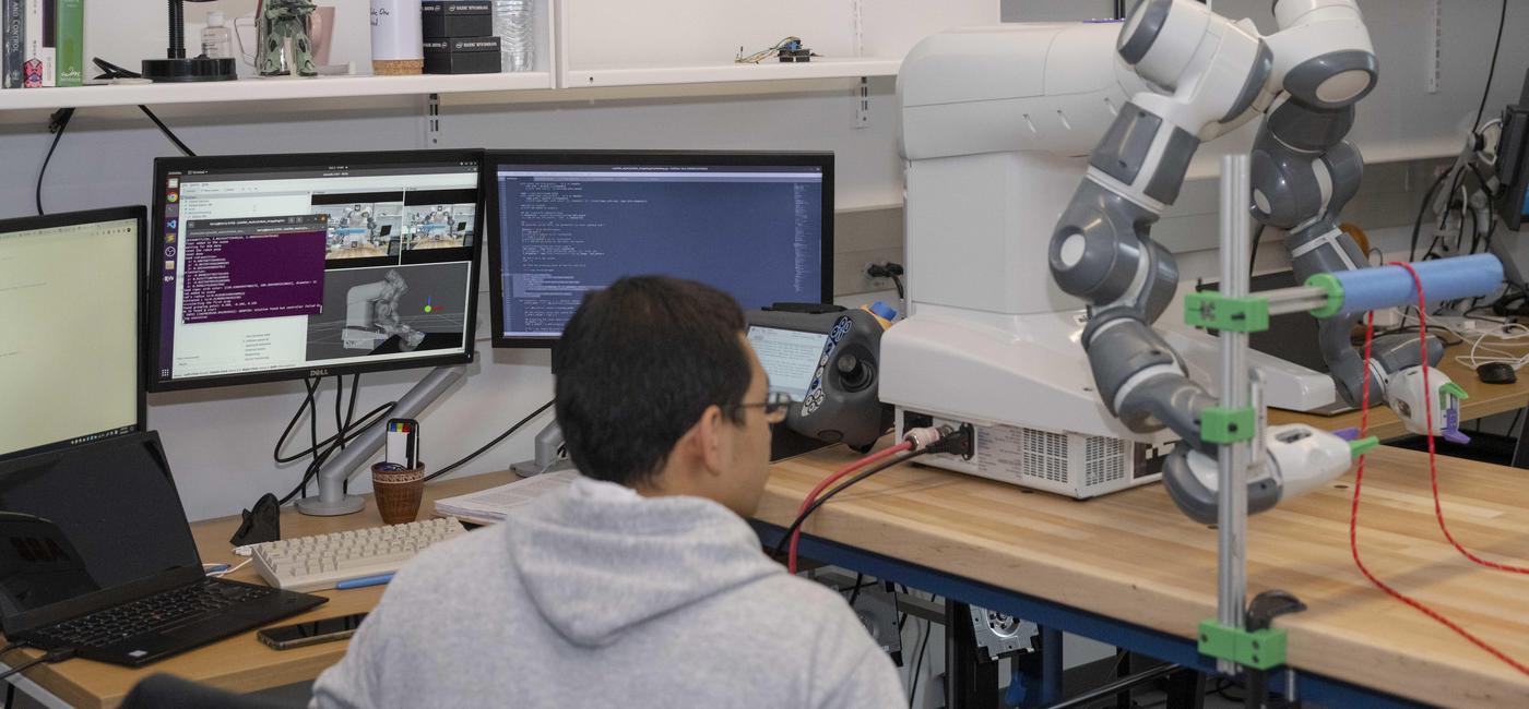 Student in robotics lab in front of dual monitor