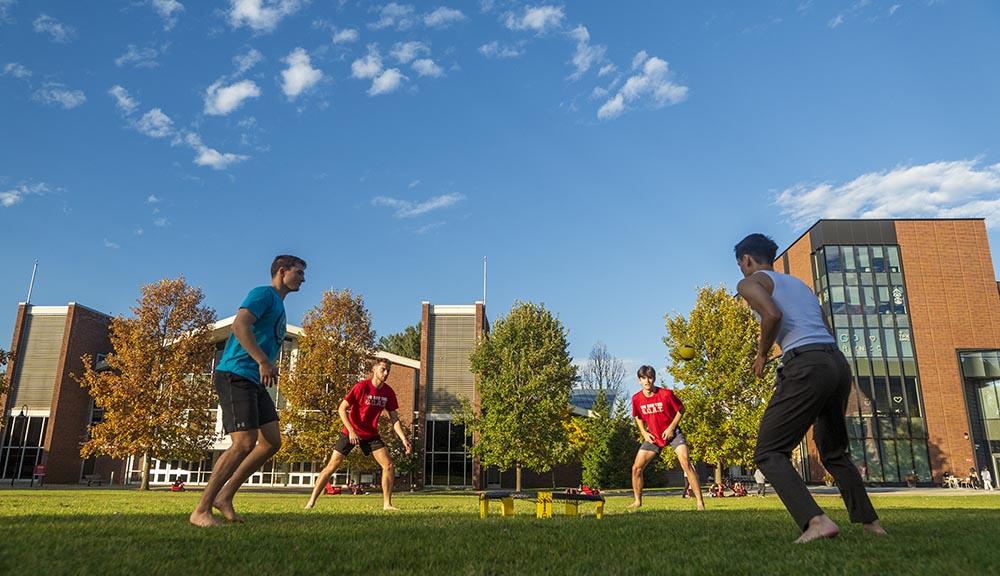 Students play spikeball on the Quad during a sunny day.