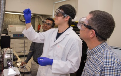 PhD student Lite Zho (materials  science and engineering), and Aaron Deskins examine  a sample of a material being tested as a possible  replacement for silicon in solar photovoltaic cells.