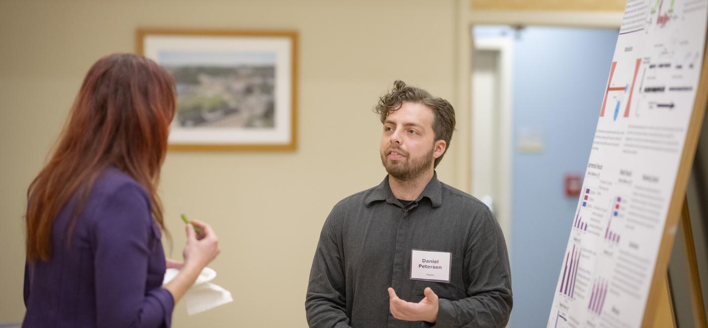 Physics PhD student Daniel Peterson presenting a poster at the A&amp;S D.O.S.E. event.