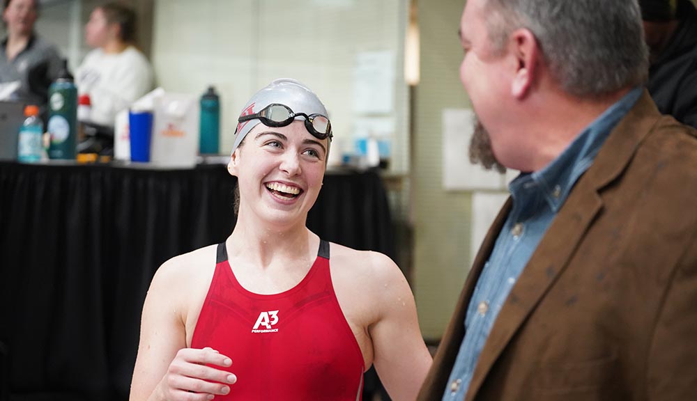 A member of the women's swim team smiles at her coach after a meet.