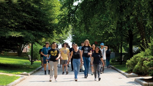 a group of students walking on campus on a sunny summer day