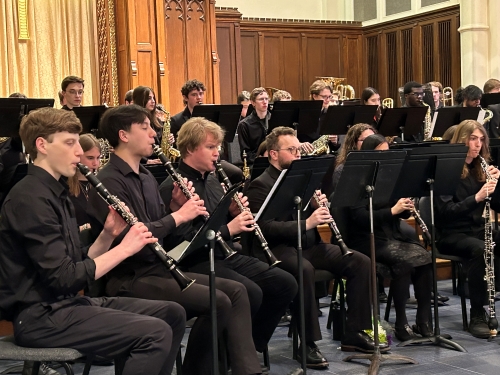 WPI Concert Band members play instruments, seated in rows, inside concert hall at Worcester Area Mission Society