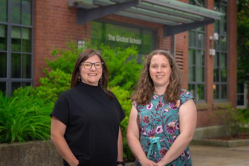 Krista Miller and Kathleen Head, smiling, seen standing in front of the Global Project Center Building on the WPI campus